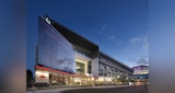 External street view of South Brisbane's ABC Headquarter building designed by KIRK at dusk. building lit up by internal and exterior lighting. Pedestrians and cars moving about outside on street and path.