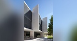 ABC headquarters building in full sun. Green space park and tree off to right. Black and white building with outdoor seating on ground level concrete paved patio.