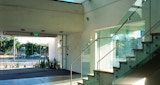 ground floor lobby facing out through large glass entry doors to street of Cutting Edge Postproduction facility building. Architecture design by KIRK Studio. Glass balustrade staircase. Afternoon sunlight streaming in through windows.