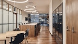 Staff lunchroom inside Melbourne office with frosted glass partition walls. Timber floating island with double side chair stool seating and circular ring downlighting.