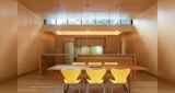 Kitchen and dining view inside KIRK designed West End house. Simple timber table with yellow chairs feature at the centre of the fully timber lined home.